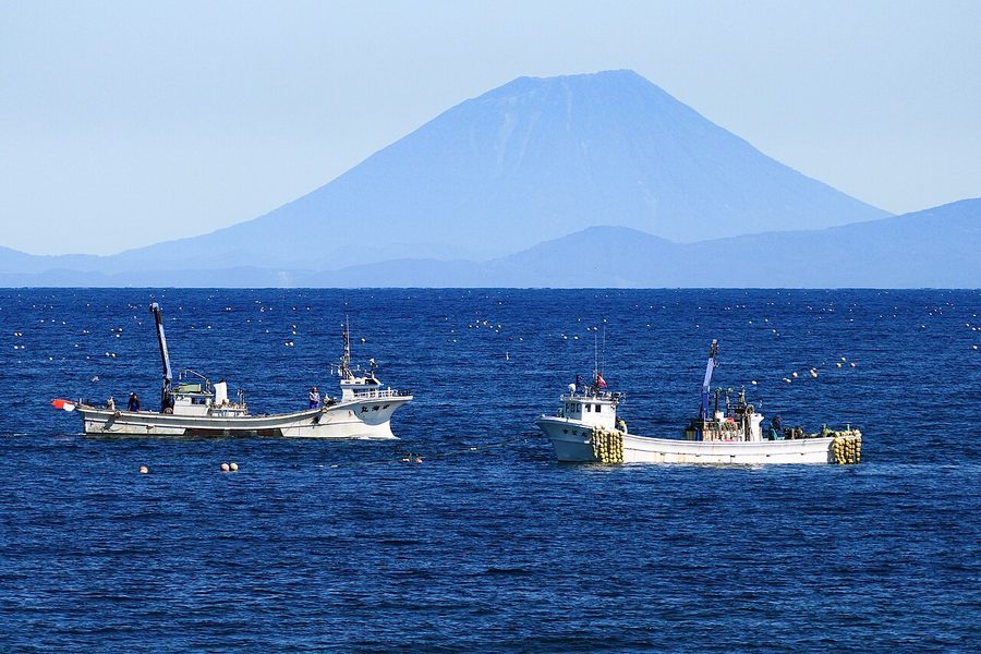 内浦湾（噴火湾）を行く漁船と、遠くに見える羊蹄山