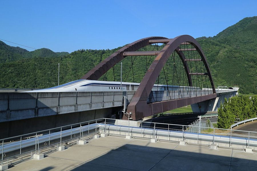 リニアモーターカー(L0系)が、山々に囲まれたリニア実験線の高架橋を走行している様子