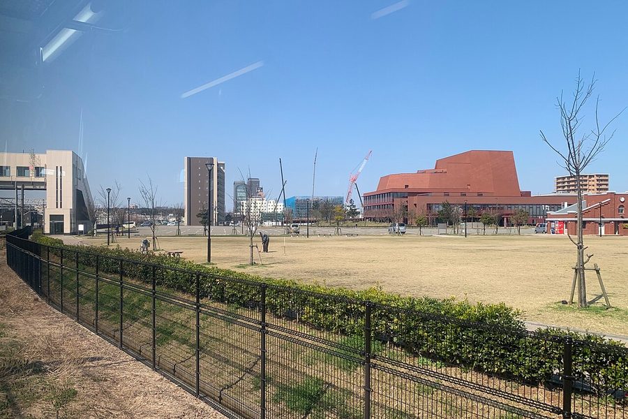 柏崎市文化会館アルフォーレ（赤茶色の建物）と、手前に広がる芝生の駅前公園